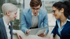 Three professionals discussing financial documents at a meeting table