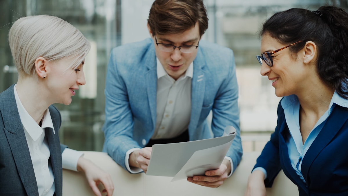 Three professionals discussing financial documents at a meeting table