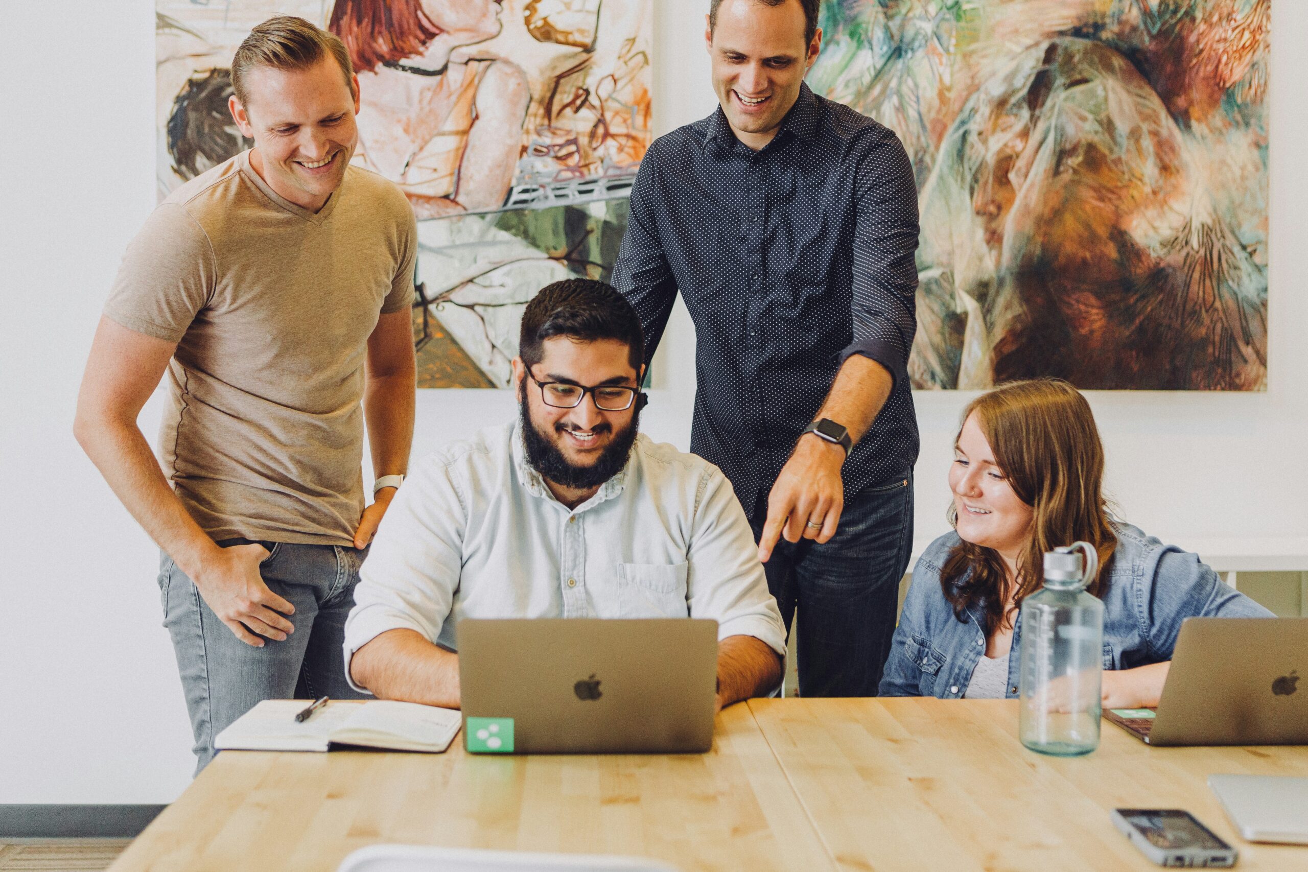 four coworkers smiling around laptop at table