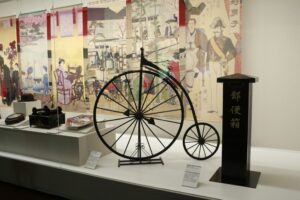 Vintage penny-farthing bicycle and historical japanese artifacts on display.